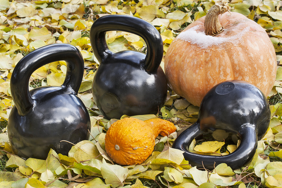 three heavy iron kettlebells outdoors in a fall scenery with pumpkin and squash - outdoor fitness concept